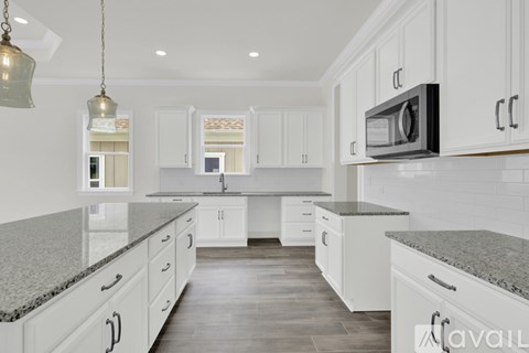 A kitchen with white cabinets and a granite countertop.