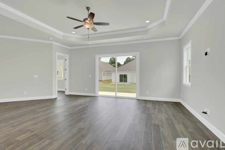 A spacious room with a ceiling fan and sliding glass doors leading to a backyard.