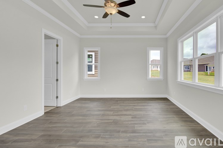 A room with a ceiling fan and wood flooring.