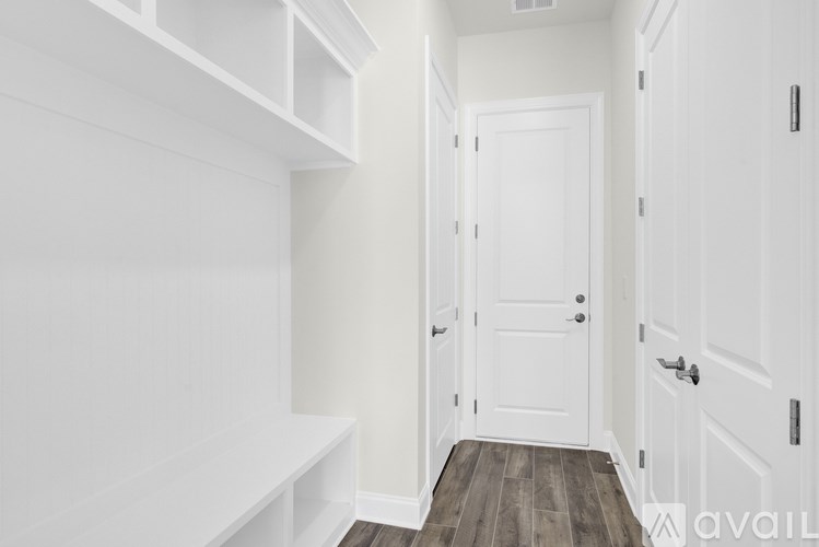 A hallway with white doors and a white bench.