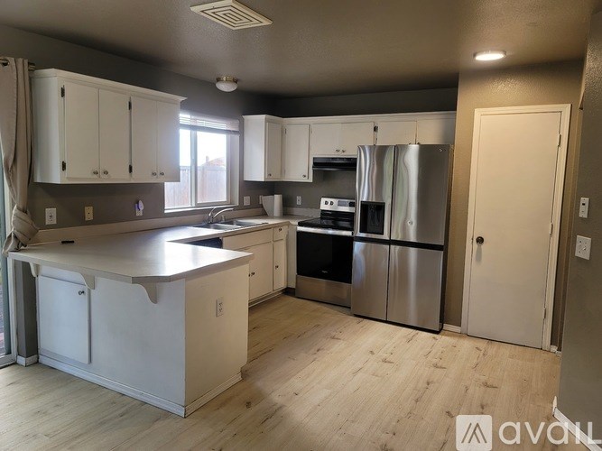 A kitchen with white cabinets and a stainless steel refrigerator.