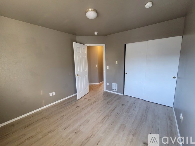 A room with a white door and a wooden floor.
