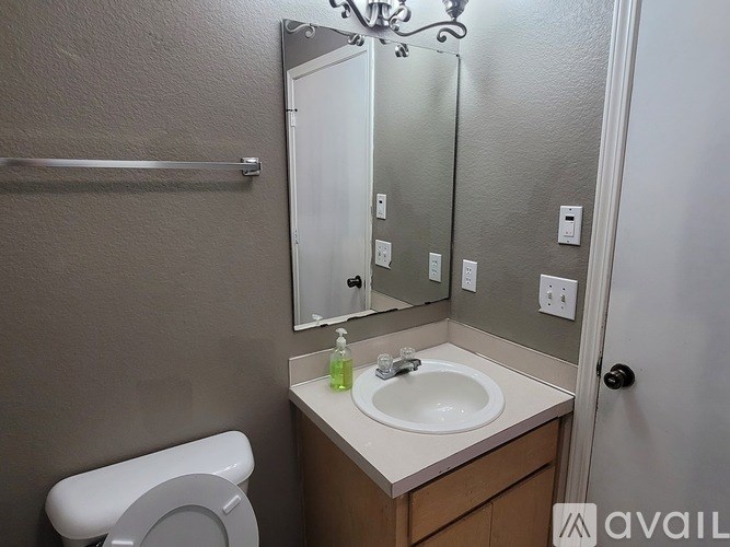 A bathroom with a toilet, sink, mirror, and towel rack.