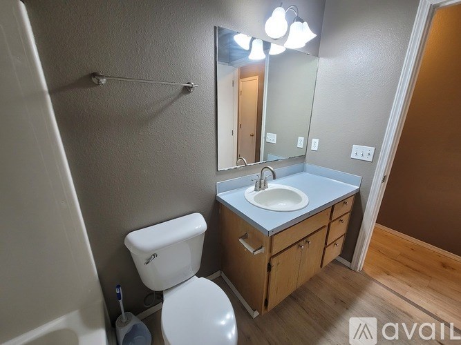 A bathroom with a toilet, sink, and mirror.