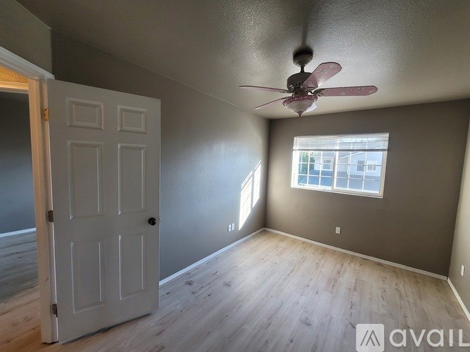 A room with a ceiling fan and a door leading to another room.