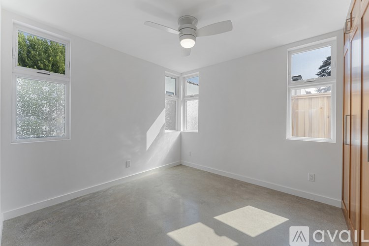 A spacious room with a ceiling fan and two windows.
