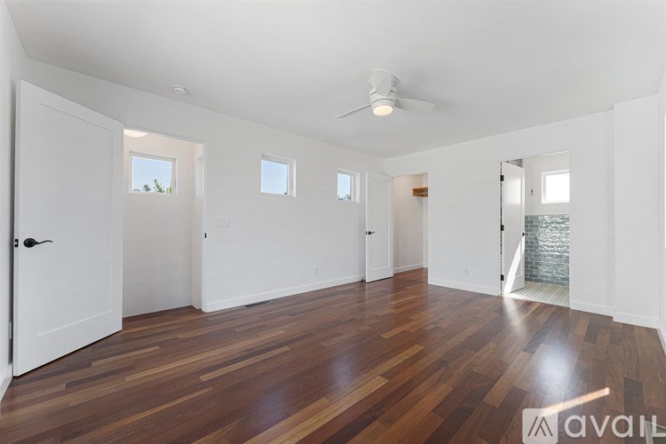 A spacious room with wooden floors and white walls.
