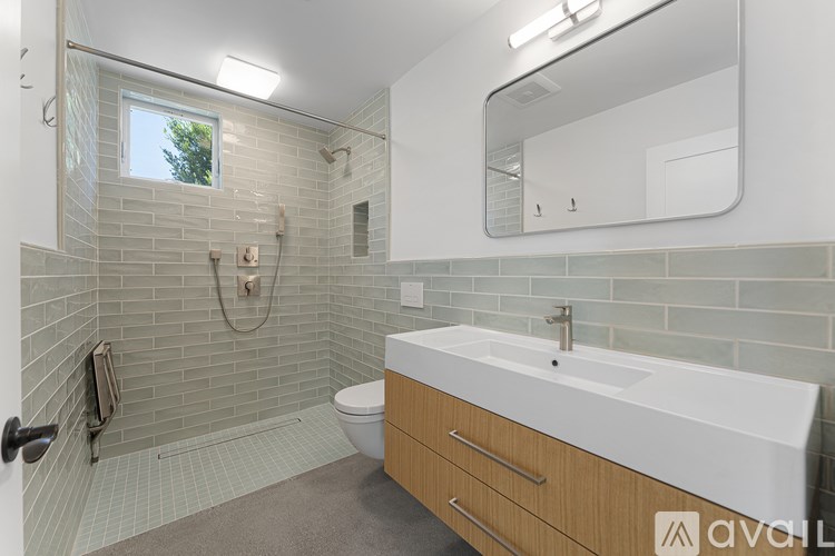 A bathroom with a white sink and a grey tiled shower.