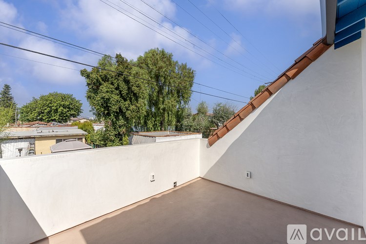 A balcony with a white wall and a brown roof.