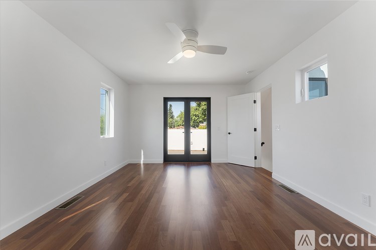 A spacious room with wooden floors and a ceiling fan.