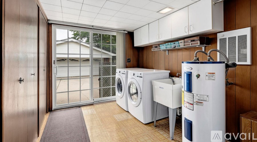 A small laundry room with a washer and dryer, a refrigerator, and a door leading outside.