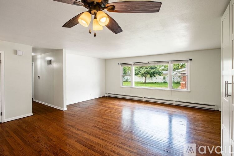 A room with a ceiling fan and wooden flooring.