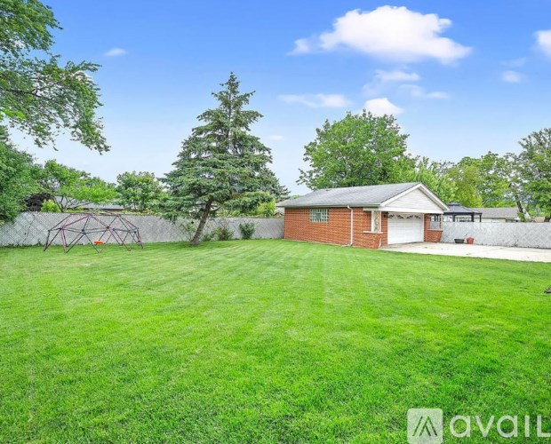 A house with a green lawn and trees in the background.