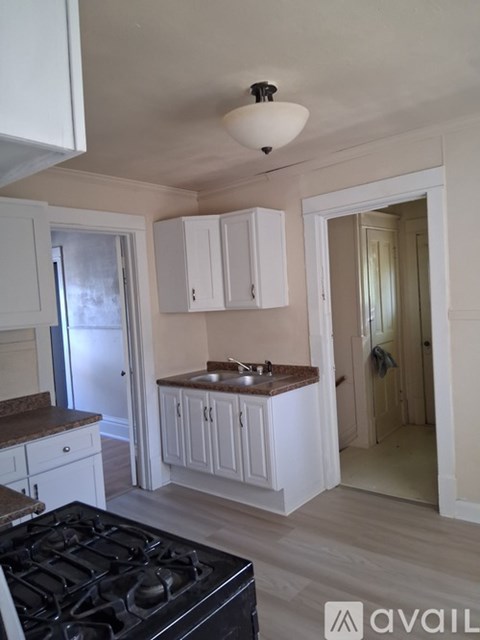 A kitchen with a black stove top oven and white cabinets.