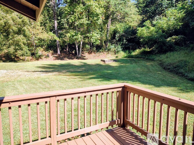 A wooden deck overlooks a grassy field and trees.