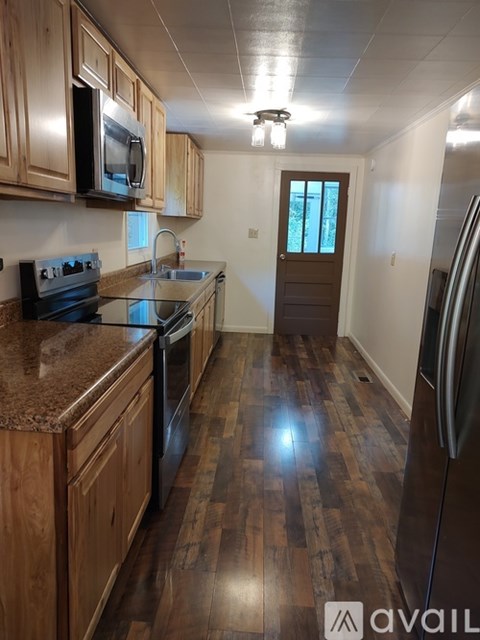 A kitchen with wooden cabinets and a black refrigerator.