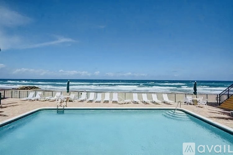 A pool with chairs and a view of the ocean.