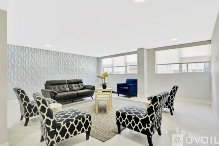 A living room with a grey sofa, a blue armchair, and a patterned ottoman.