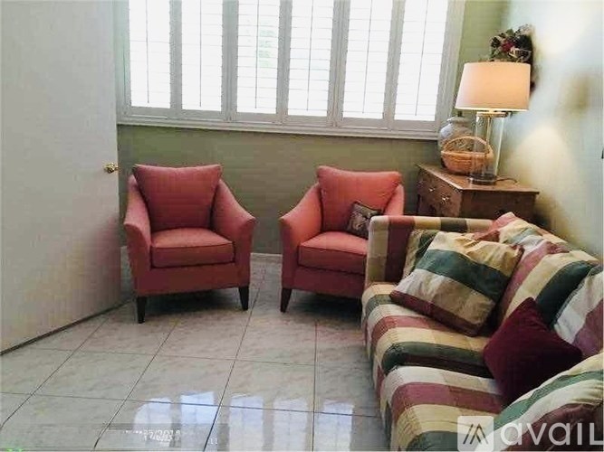 Two red chairs and a sofa with striped cushions in a room.