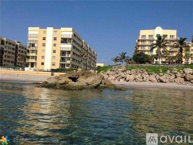 A beachfront with buildings and palm trees.