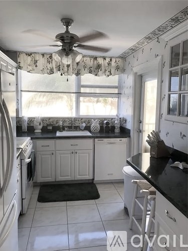 A kitchen with a fan and a window with curtains.
