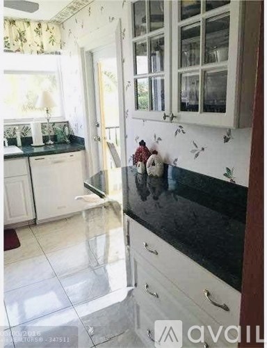 A kitchen with white cabinets and a black countertop.
