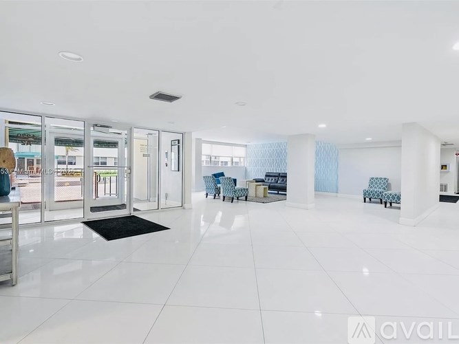 A spacious lobby with white floors and a black mat on the floor.