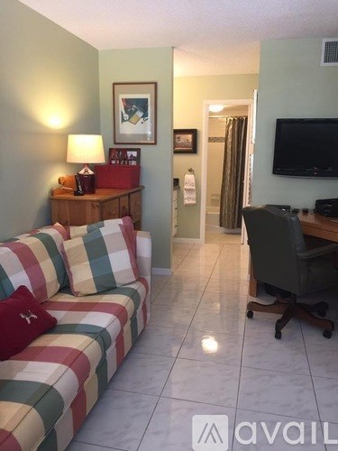 A living room with a striped couch, a television, and a desk with a chair.