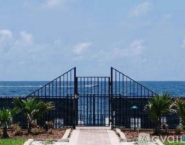 A black gate leads to a beachfront property.