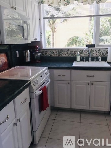 A kitchen with white cabinets and a black countertop.