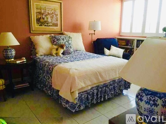 A bed with a white blanket and a blue and white patterned comforter.