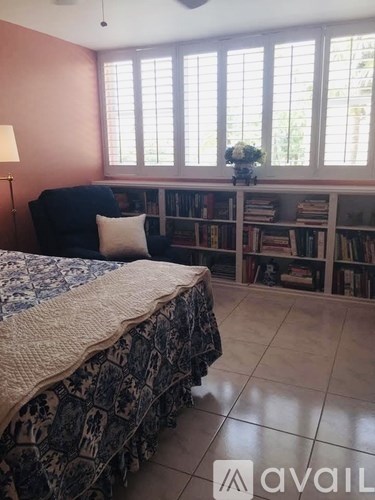 A bedroom with a bed, a chair, and a bookshelf.