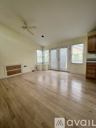 A spacious room with wooden flooring and a ceiling fan.