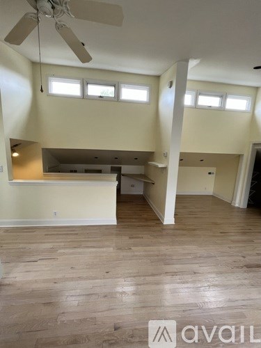 A spacious room with wooden floors and a ceiling fan.