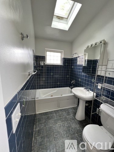 A bathroom with a skylight, blue tiles, and a white sink.