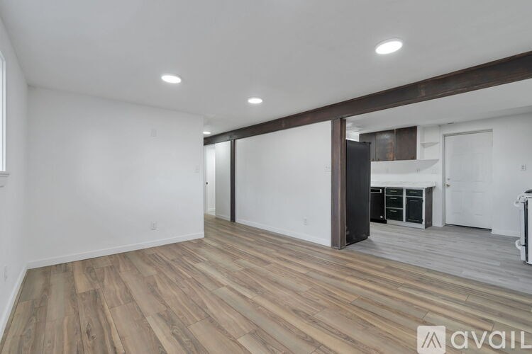 A spacious room with wood flooring and white walls.