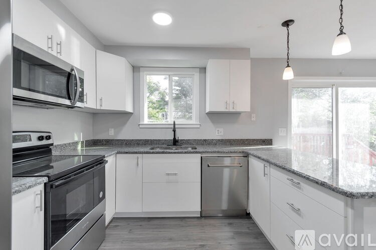 A modern kitchen with white cabinets and stainless steel appliances.