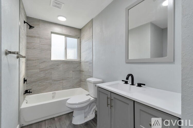 A modern bathroom with a white tub, toilet, and sink.