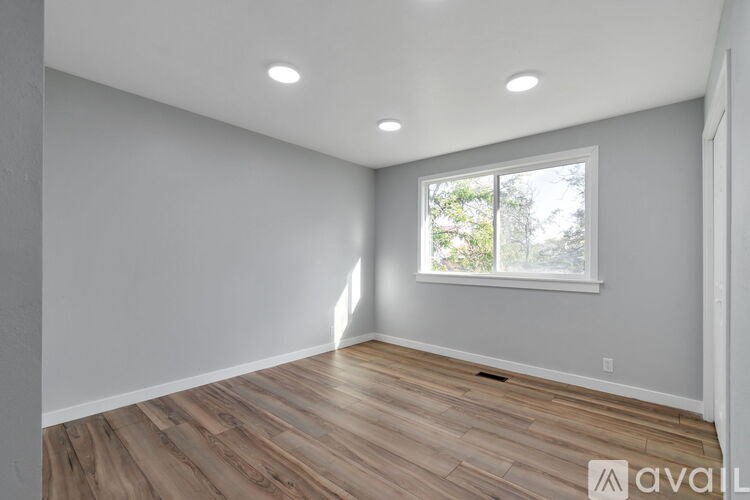 A spacious room with wooden flooring and a window.
