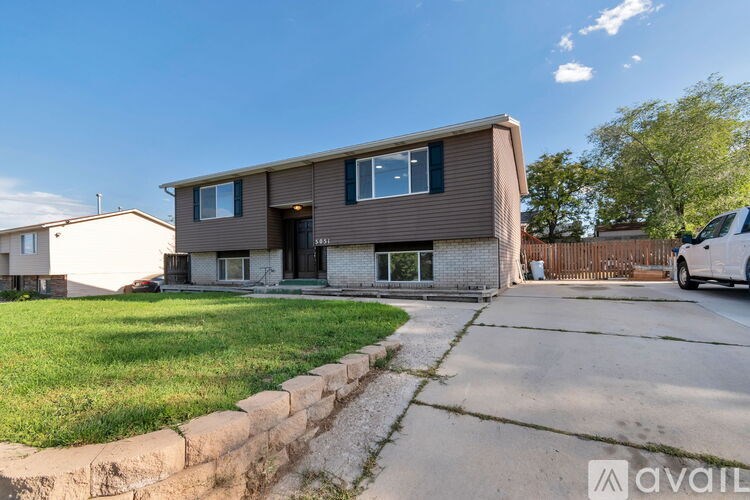 A house with a brown siding and a white car parked in front.
