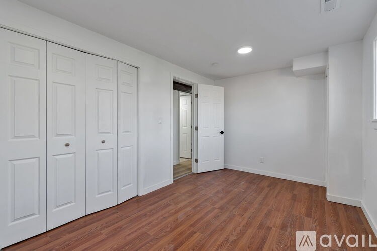 A room with wooden flooring and a window overlooking trees.