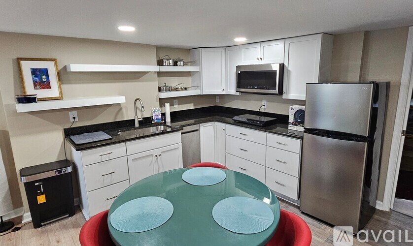 A kitchen with white cabinets and black countertops.