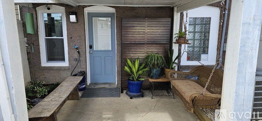 A small patio with a couch, plants, and a door.