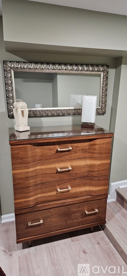 A bathroom with a wooden vanity and a mirror above it.