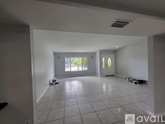 A spacious room with white walls and a tiled floor, currently under renovation.