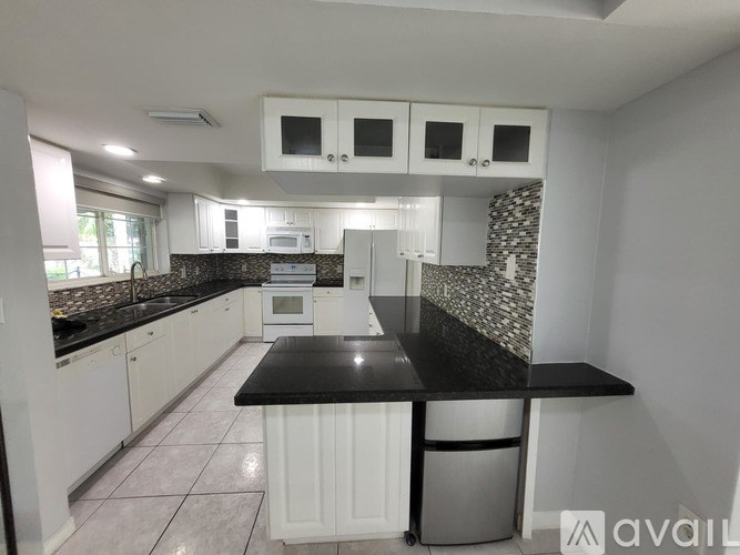 A kitchen with white cabinets and black countertops.