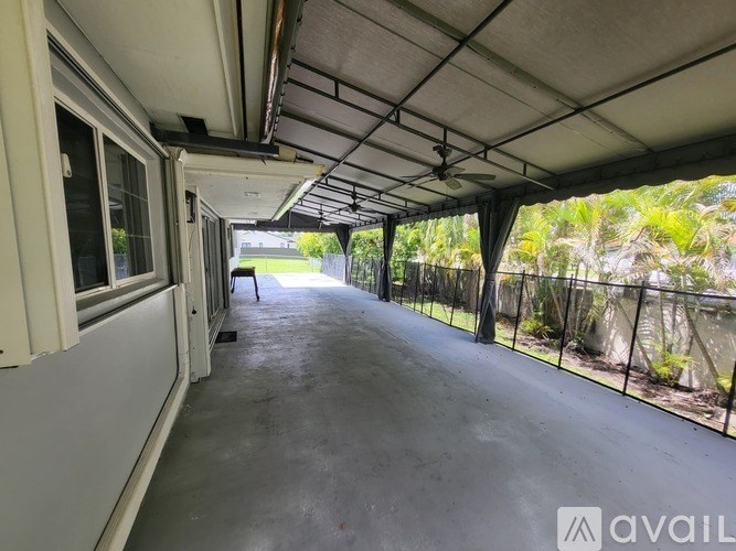 A long, narrow, covered outdoor area with a concrete floor and a metal fence on one side.