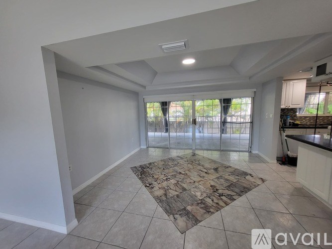 A spacious room with a marble floor mat and sliding glass doors leading to a balcony.