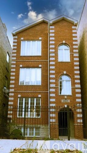 A red brick building with white windows and a black gate.