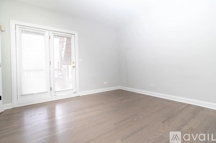 A room with a white door and wooden flooring.